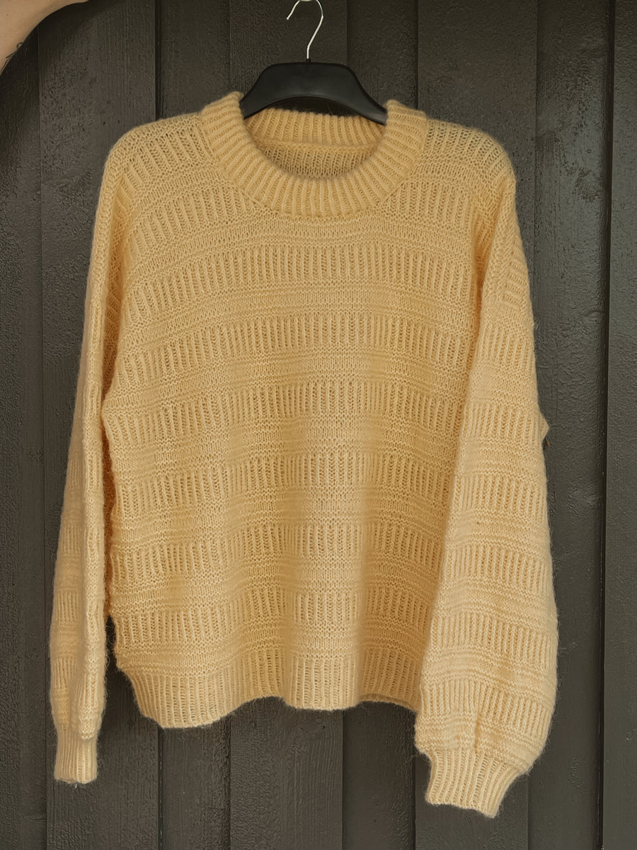Gul Coffee Sweater på galge, med raka ärmar · ärmarna plockas upp och stickas runt ner till resåren