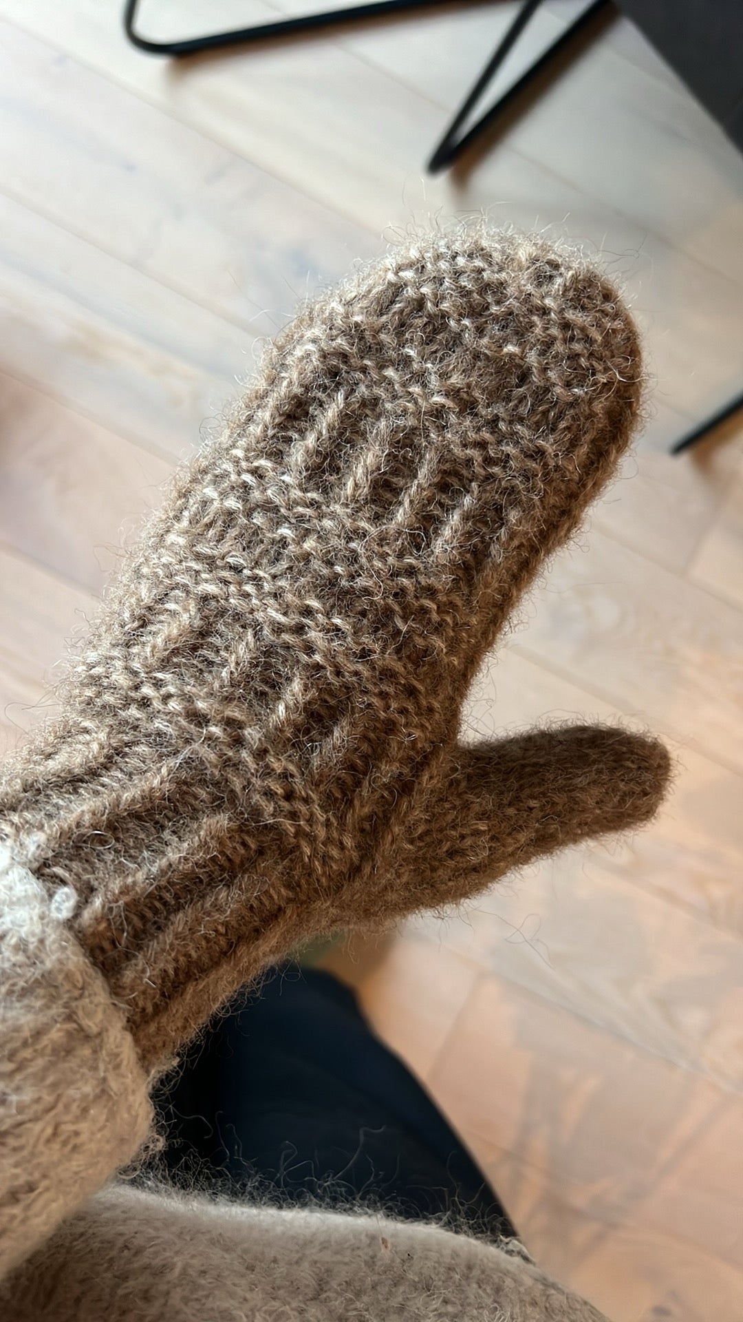 Coffee Mitten på handen med tummen ute, på ett trägolv · storlekar från 3-6 år till vuxen L