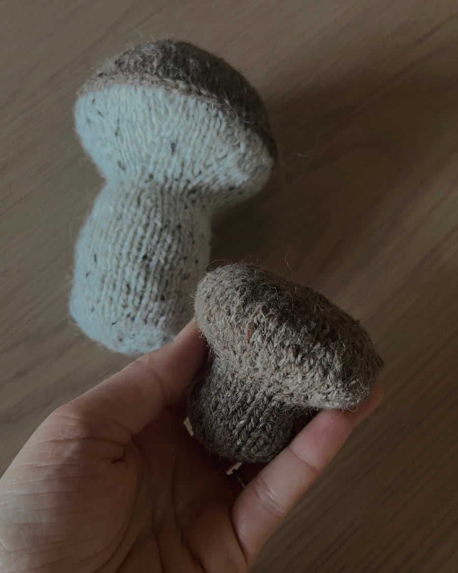 Två stickade svampar i brunt och naturvitt, hatten hållen i en hand · stickas runt utan sömmar