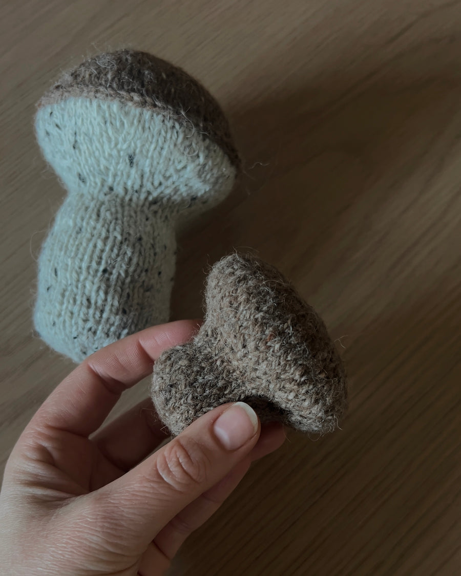 Två stickade svampar på ett ljust träbord, hatten i en hand · börjar med magic ring