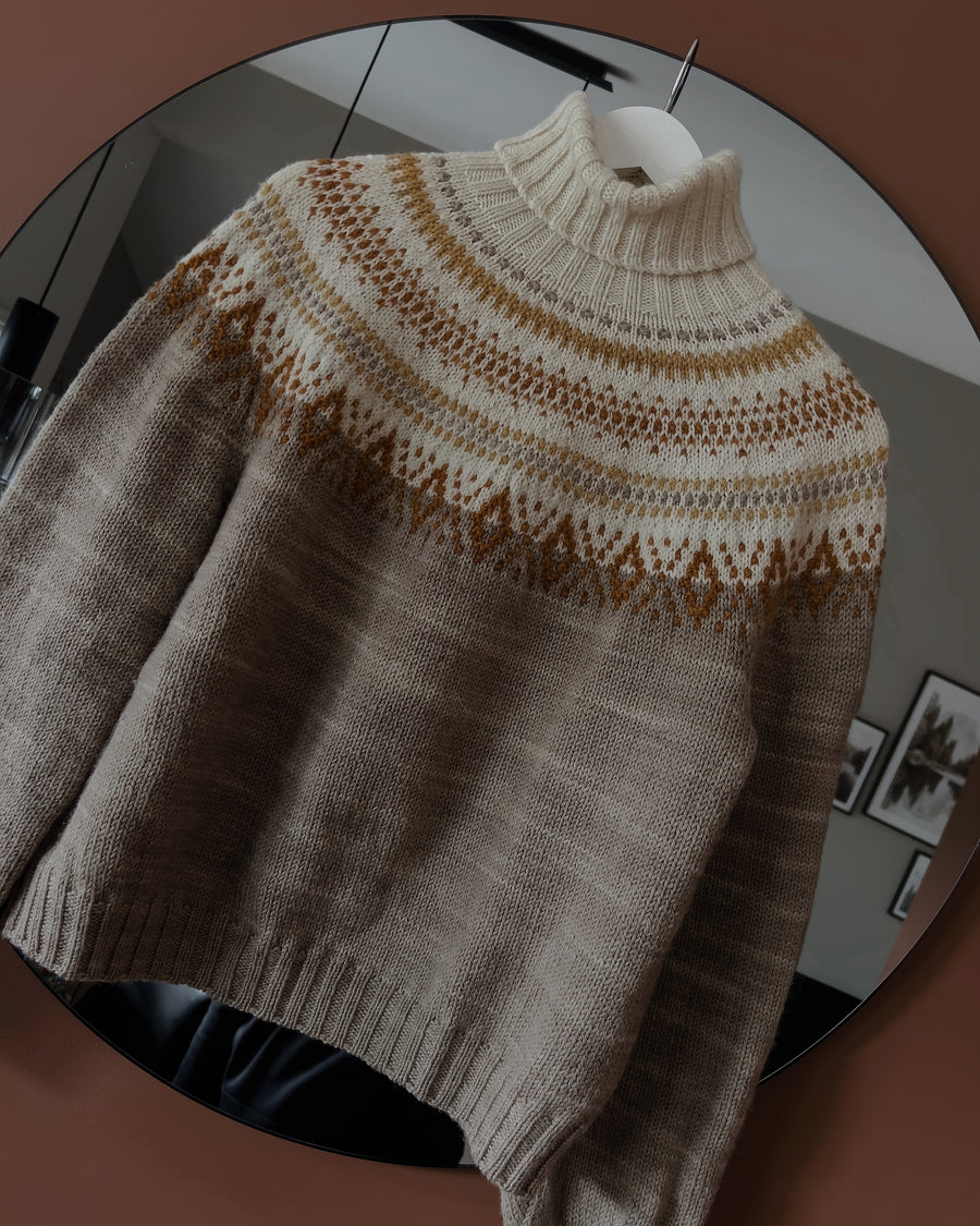Tales of Patagonia Sweater med hög halskant framför en spegel · mosaikstickning formar det runda oket