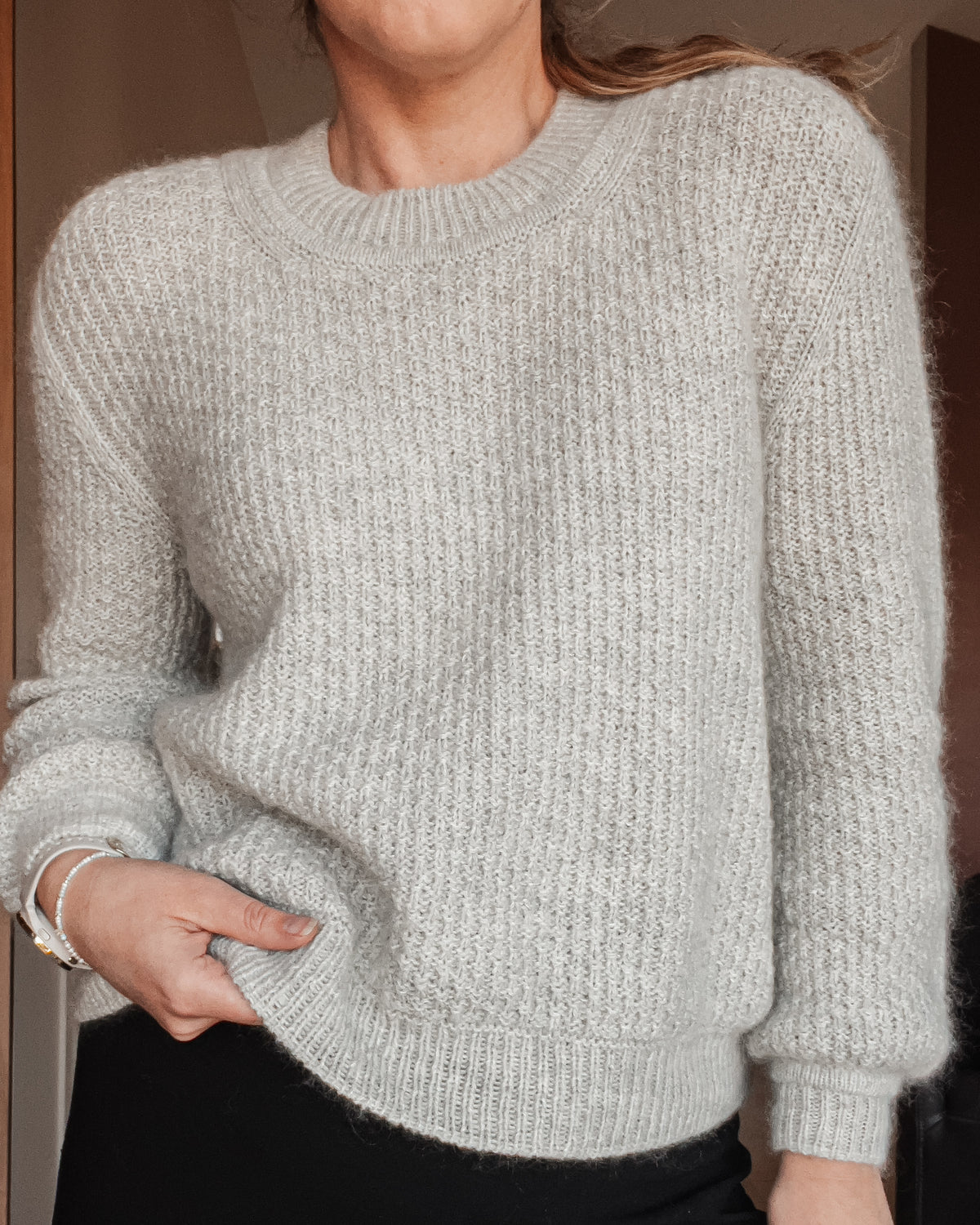 Närbild på Mistlight Sweater bärd, med rund halskant och ribbad nederkant · ärmar och bål stickas runt i strukturen
